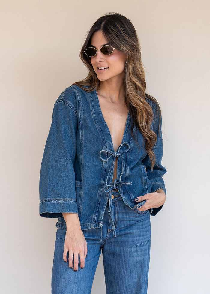 Indigo denim jacket with tie-front neckline, functional pockets, and 3/4 sleeves